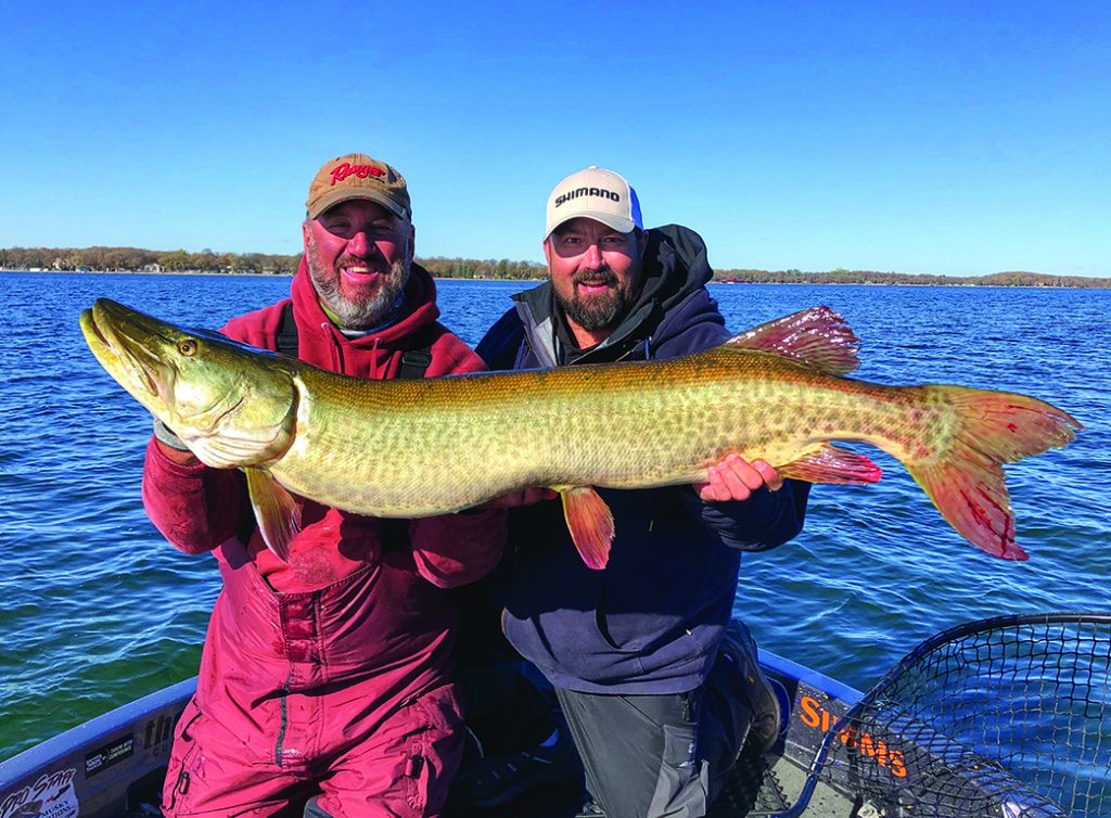 John Mich and Scott Kolpin smile over the giant musky they caught while fishing with the author.